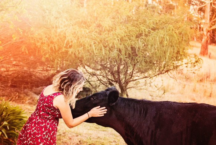A képen egy vegán lány és egy tehén látható.